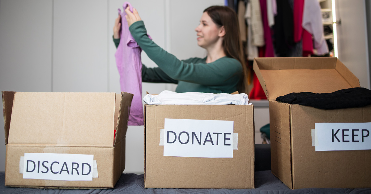 A woman sorts through old clothes to decide what to discard, what to donate, and what to keep.